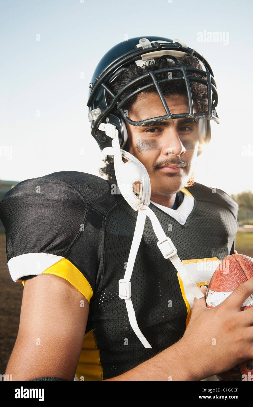 Tanned guy with curly hair in sports clothes, holds a football in his hands  Stock Photo