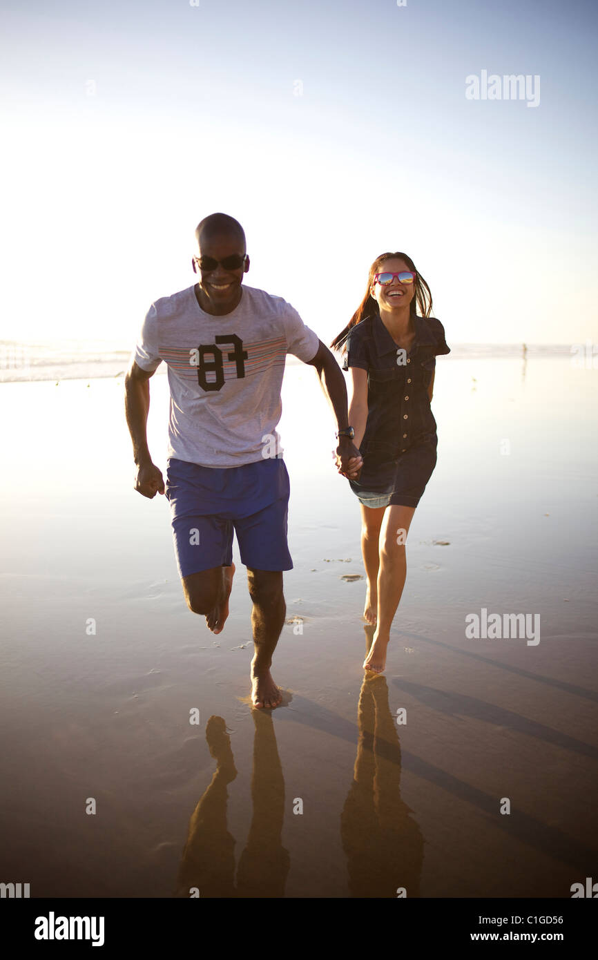 Happy couple holding hands and running on beach Stock Photo - Alamy
