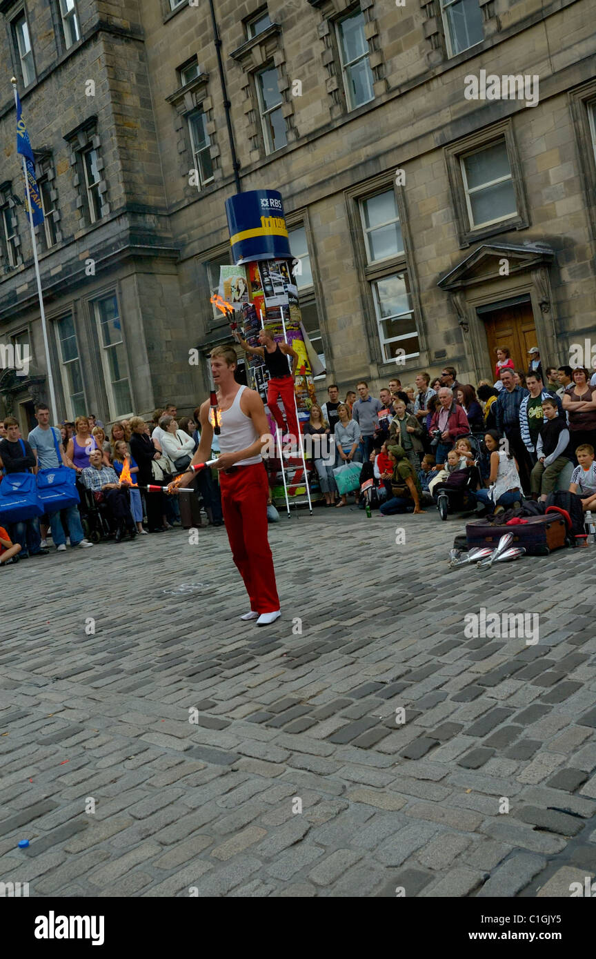 EDINBURGH - AUG. 9: Crowd watches juggler juggling fiery batons during the Edinburgh Festival Fringe enjoying buskers street performers. Stock Photo