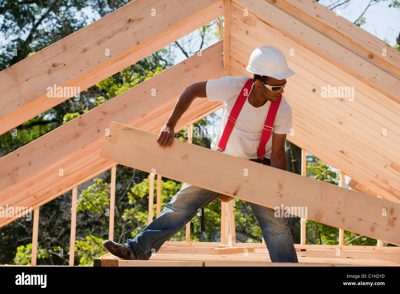 Carpenter carrying a wooden rafter Stock Photo