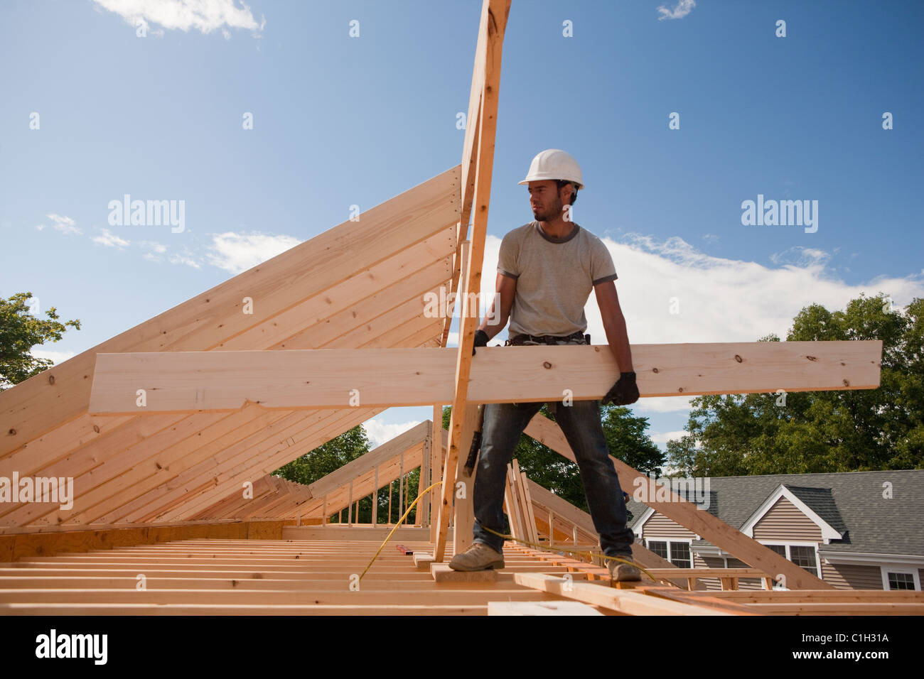 Carpenter carrying a roof rafter Stock Photo