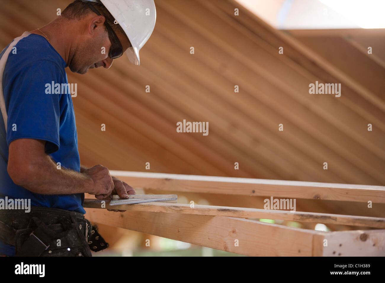 Hispanic carpenter measuring a rafter angle at a house under construction Stock Photo
