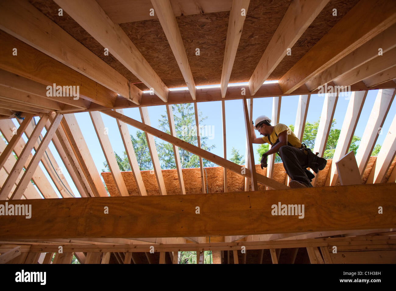 Hispanic carpenter using circular saw on rafter at a house under construction Stock Photo