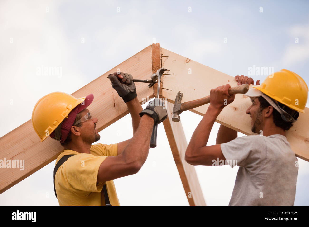 Carpenters adjusting rafters with hammer and nails and pry bar Stock