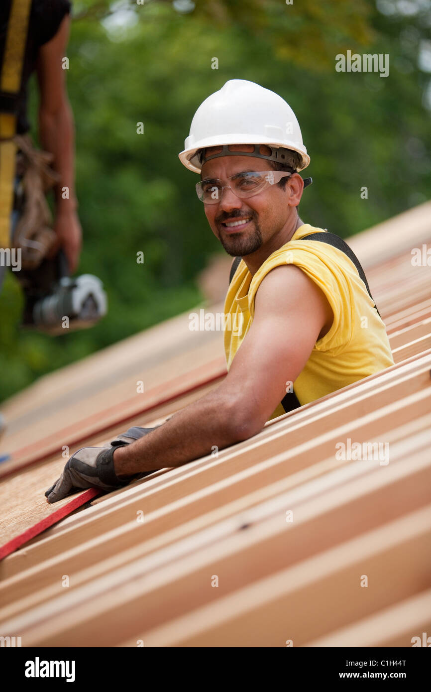 Hispanic carpenters placing roof panel at a house under construction