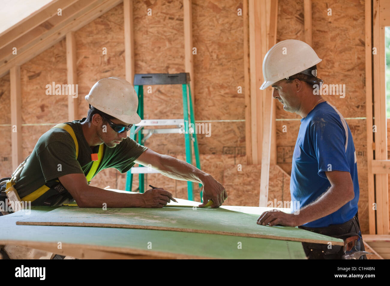 Carpenters measuring exterior sheathing at a construction site Stock Photo