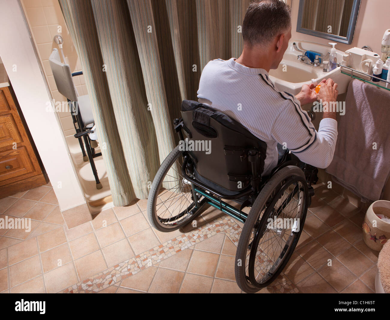 Man with spinal cord injury in a wheelchair looking at a pill bottle