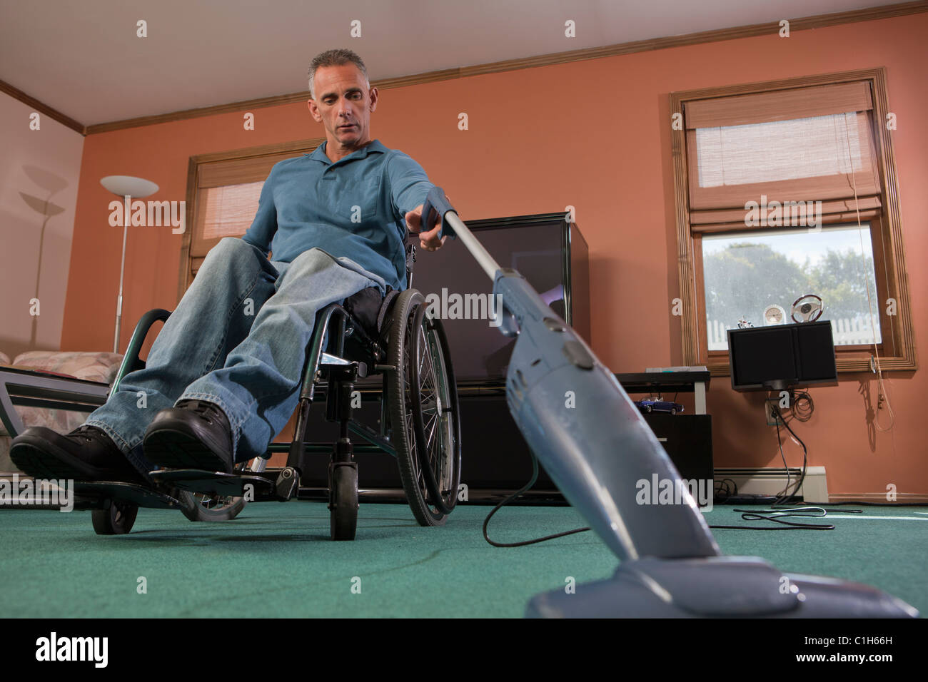 Man with spinal cord injury in a wheelchair using a vacuum cleaner at