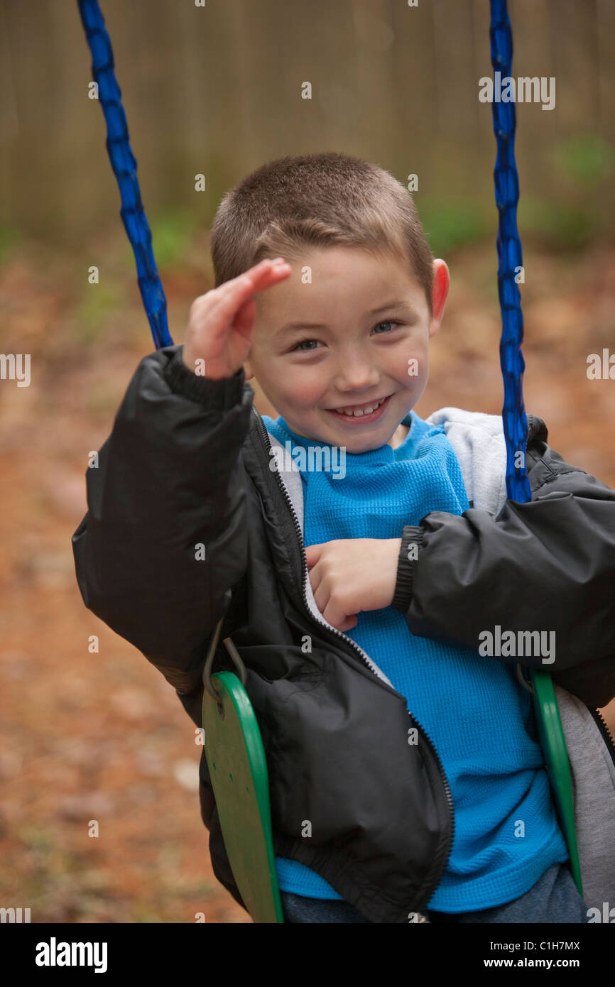 Boy signing the word 'Hello' in American Sign Language on a swing Stock Photo