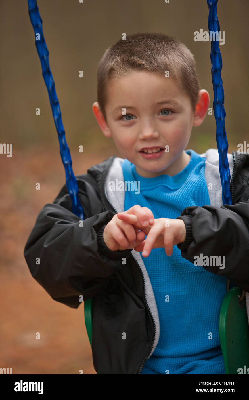 Boy signing the word 'Swing' in American Sign Language on a swing Stock Photo