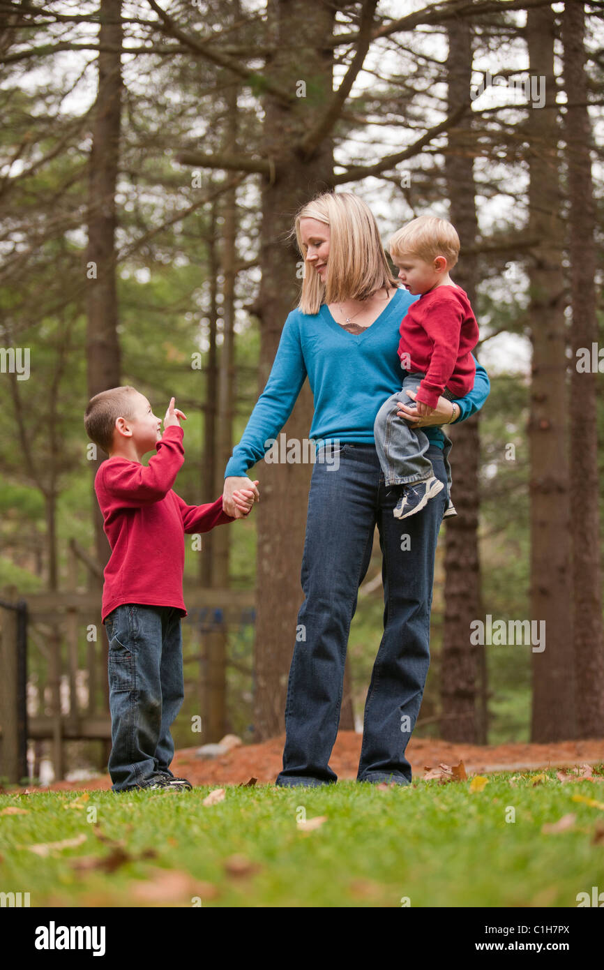 Boy signing the phrase 'I love You' in American Sign Language while communicating with his mother in a park Stock Photo