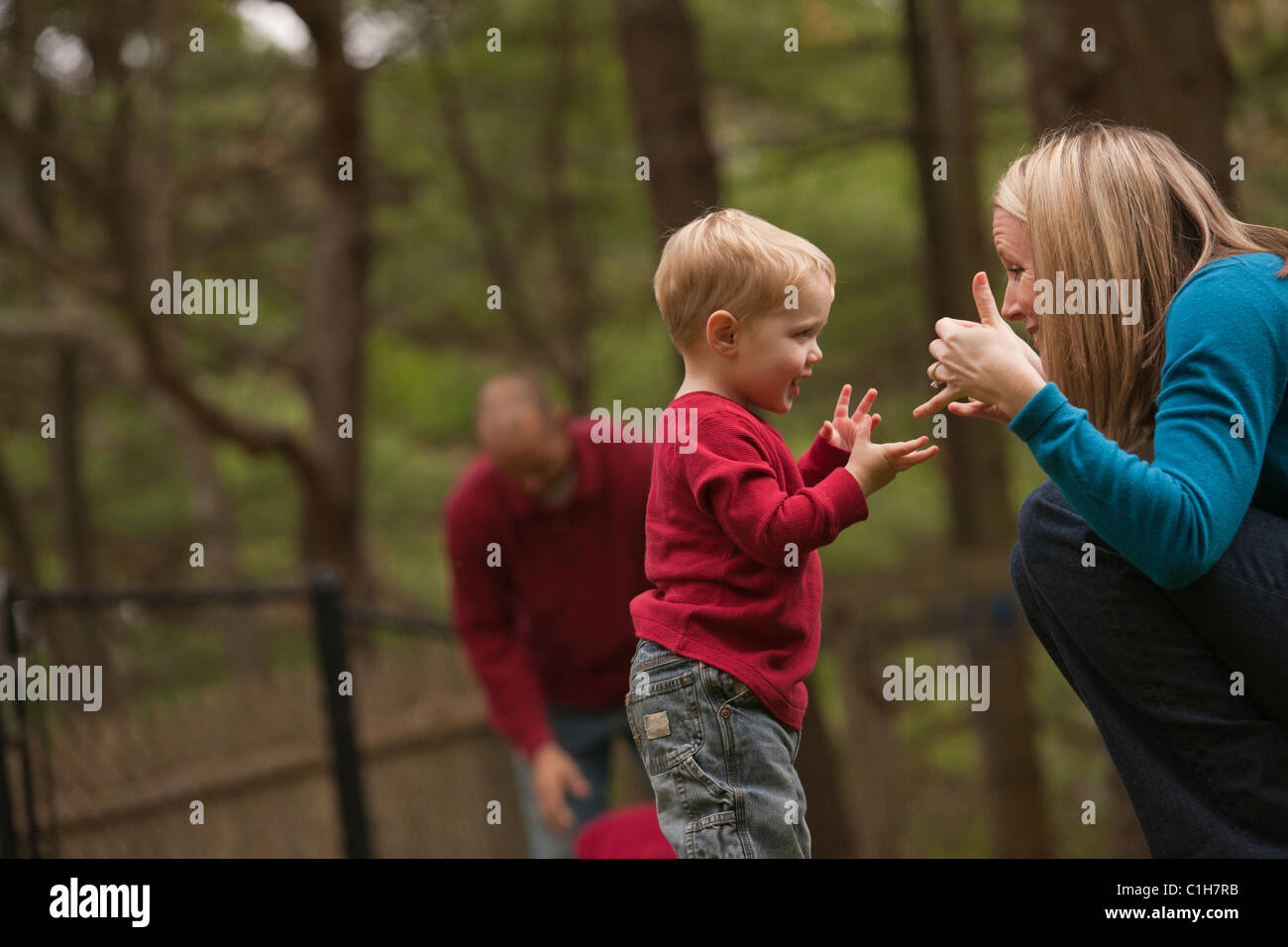 Woman signing the word 'Play' in American Sign Language while communicating with her son in a park Stock Photo