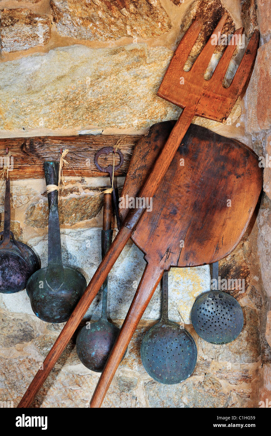 Picture of traditional oven and cooking utensils arranged against a stone wall Stock Photo