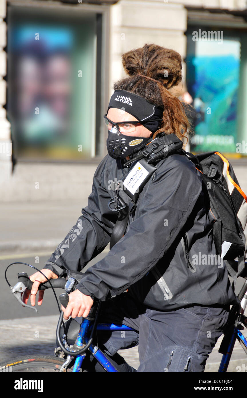 Close up woman cyclist wearing face mask against traffic exhaust fumes riding a bike in winter London England UK Stock Photo