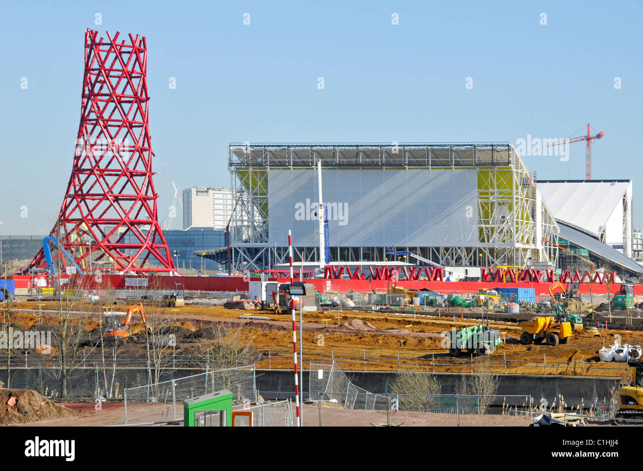 Anish Kapoor 2012 London Olympic Orbit sculpture tower under construction with temporary stands of the Aquatics centre beyond Stock Photo