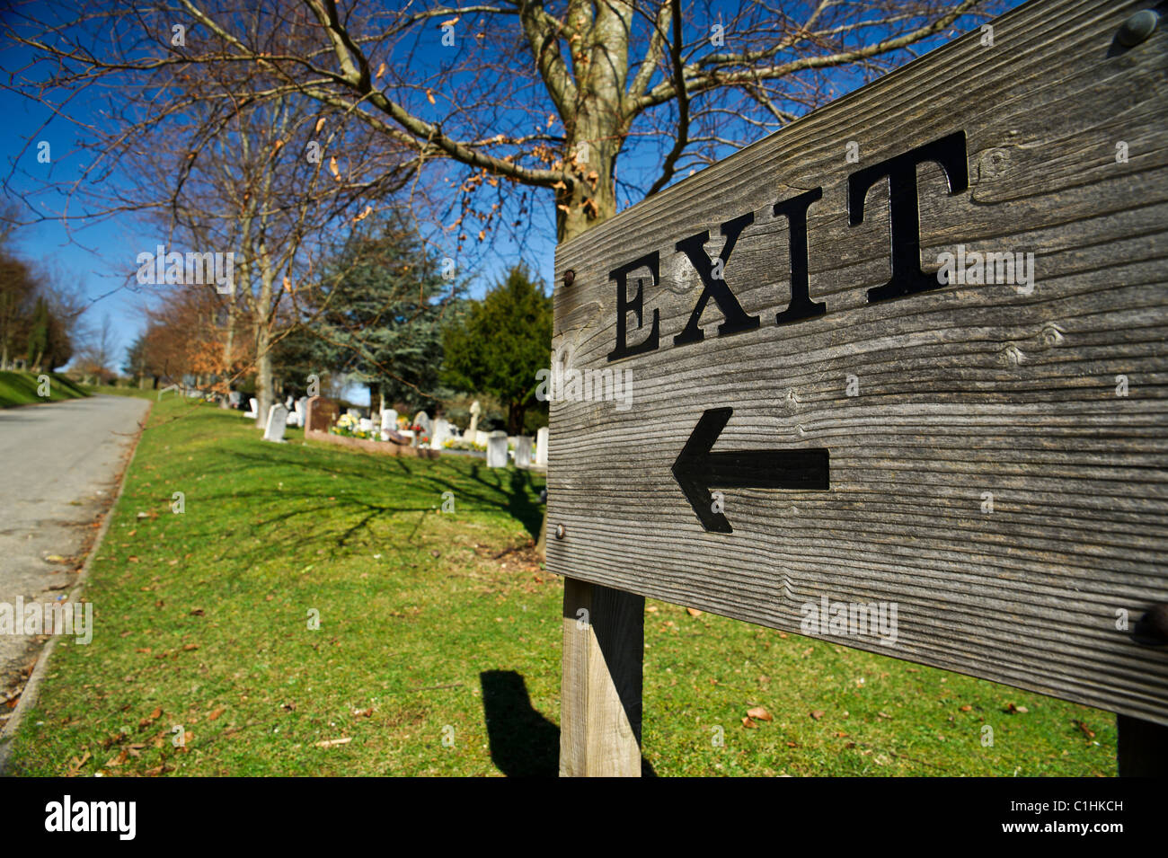A wooden exit sign in Worthing cemetery points to the left. Stock Photo