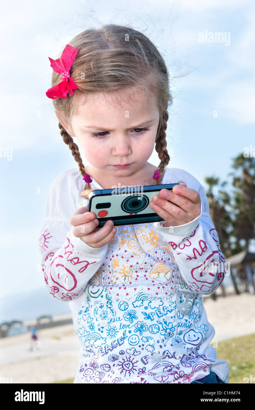 A beautiful little girl studies her video game screen. Stock Photo