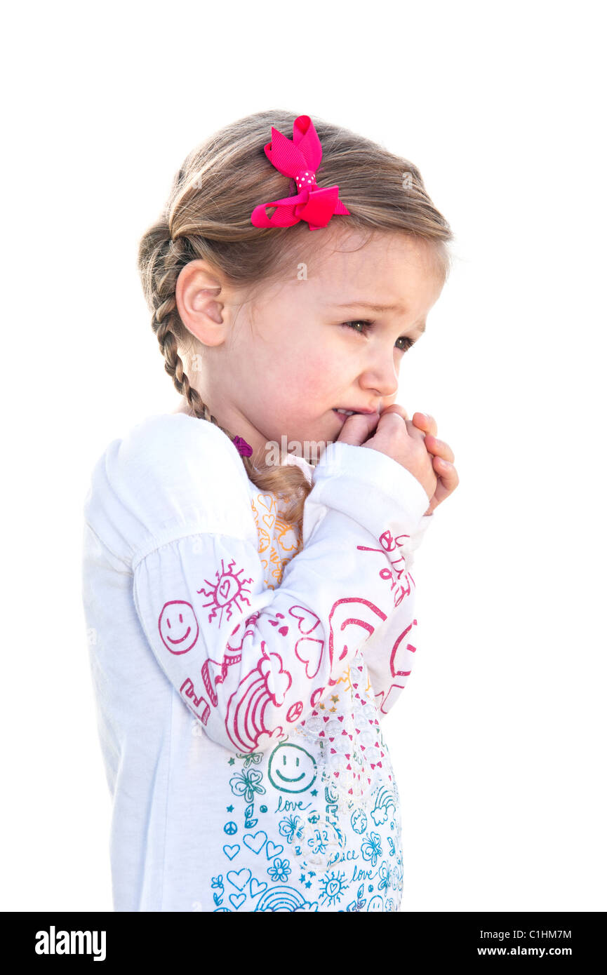 A beautiful little girl on a white background is frightened and holds her hand to her face. Stock Photo