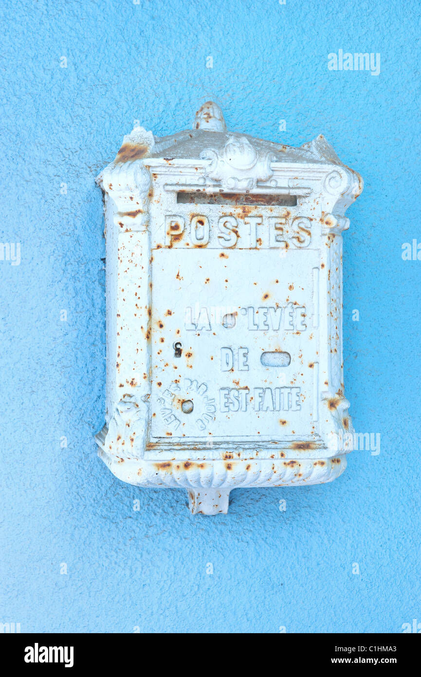 An antique mailbox from France mounted on a blue stucco wall Stock Photo