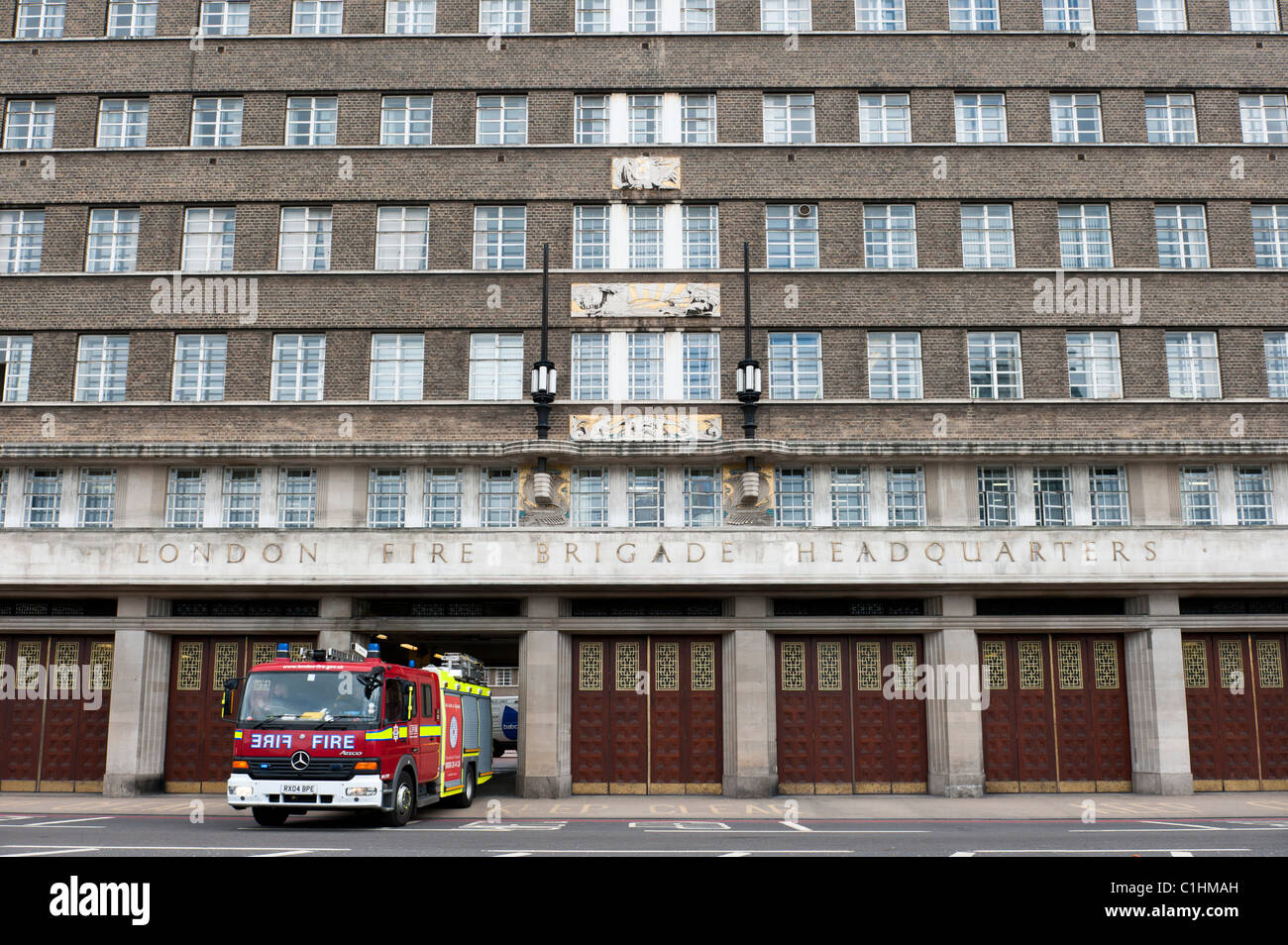 A fire engine with blue emergency lights leaves the London Fire Brigade Headquarters building on Albert Embankment. Stock Photo