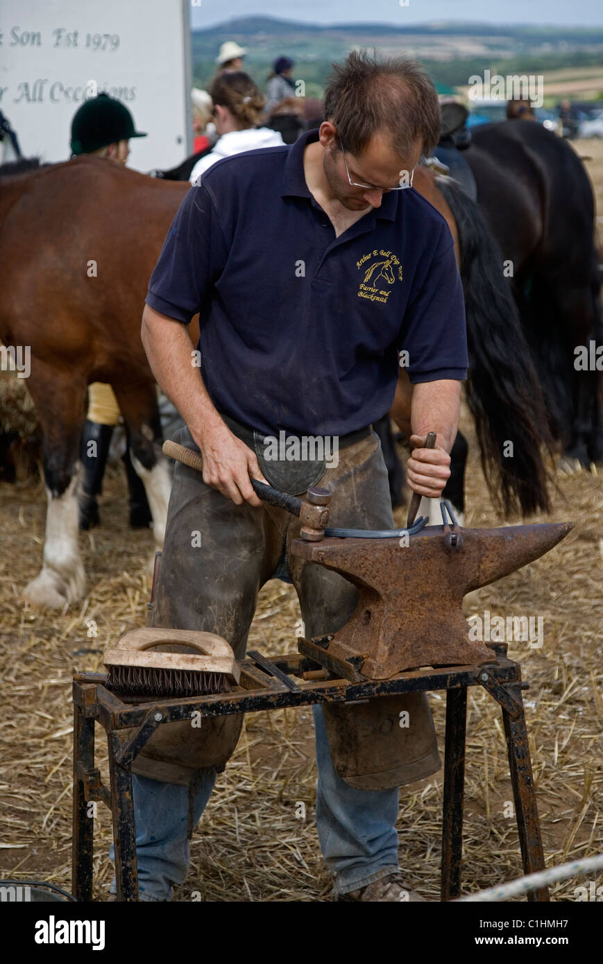 blacksmith farrier making horse shoes on an anvil at Cornwall horse and