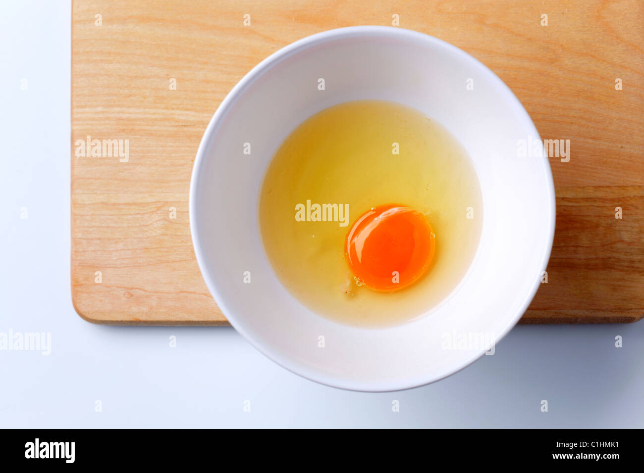 Raw egg white and yolk in a bowl - overhead Stock Photo