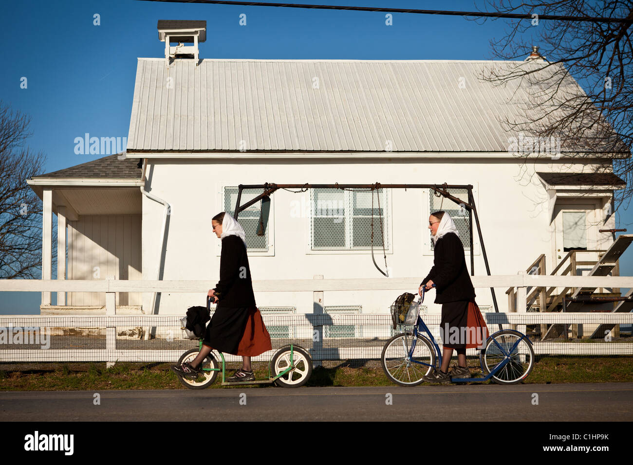 Amish girls ride a push scooter in Gordonville, PA. Stock Photo