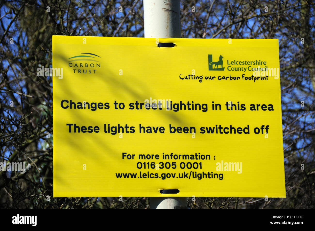 Saving Carbon or saving money? Both, apparently! Sign on a switched off lamp post by the A50 in Groby, Leicestershire, England Stock Photo
