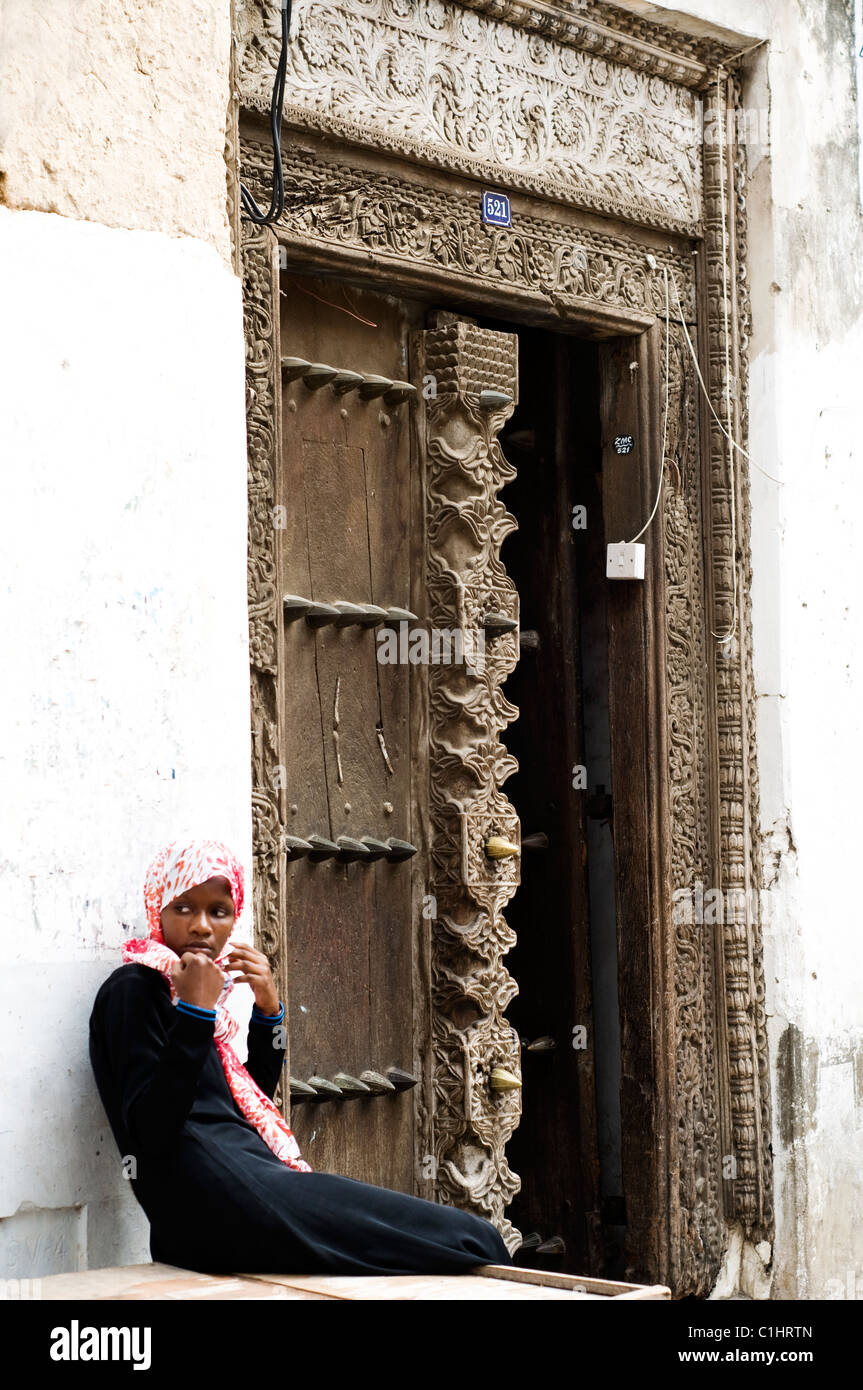 Girl outside Arabic-style door, Zanzibar, Tanzania Stock Photo