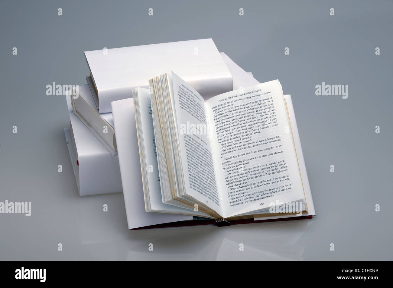 Stack of white, plain books with one book open Stock Photo