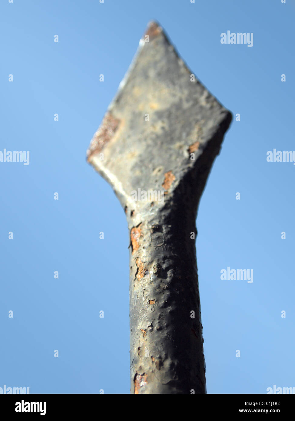 Fence rusty spearhead close-up detail against clear sky with shallow DOF Stock Photo
