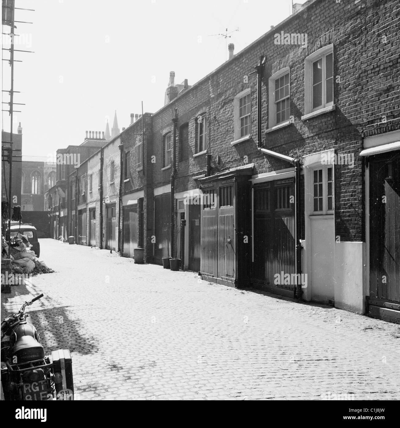 1950s, historical, a cobbled street of mews houses in Kensington, West London, with garages at street level and accommodation above. Stock Photo