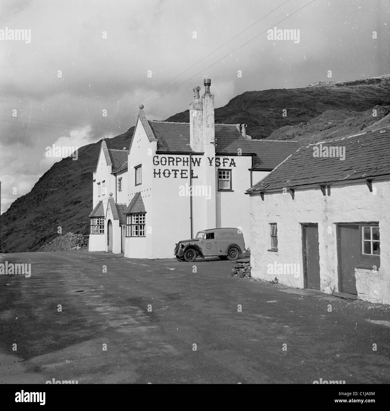 1950s, a small van of the era parked beside the Welsh hotel, Gorphwysfa, at the Llanberis Pass, Pen-y-Pas, North Wales, UK, a former coaching Inn. Stock Photo