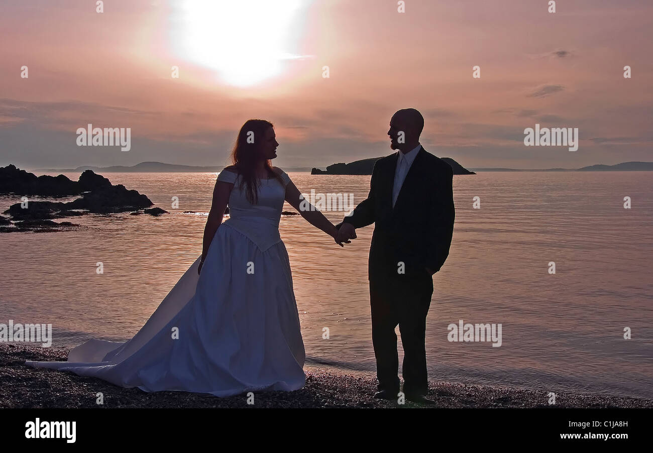 This lovely photo is a silhouette of a bride and groom holding hands at ...