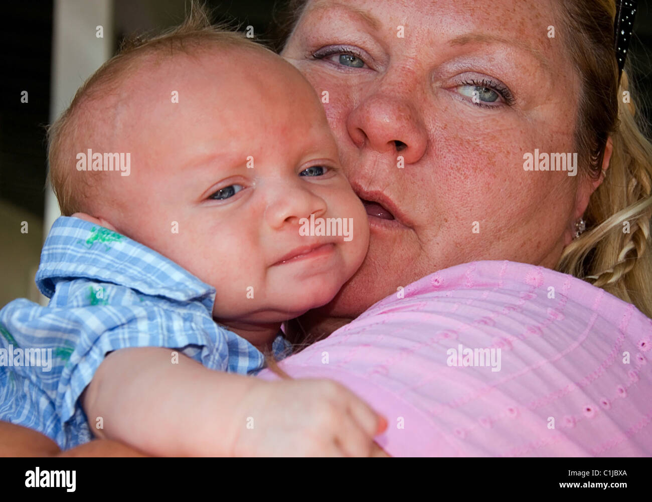 This Caucasian grandma is holding closely and cuddling her newborn baby grandson. Very closeup image. Stock Photo