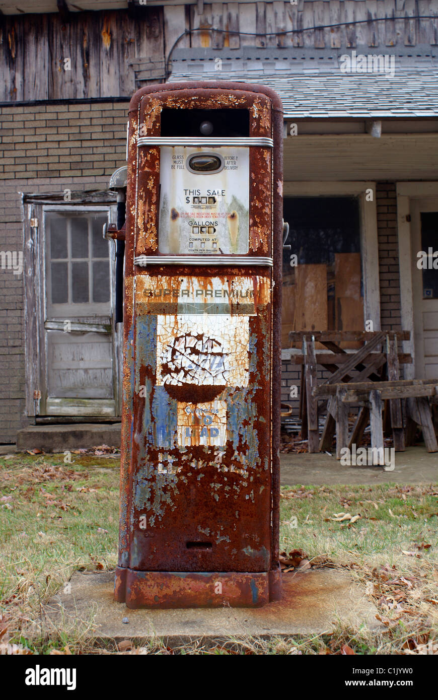 Antique American gas pump. Rusted and with chipped off paint in front of a old brick building. Logos & brand names are removed. Stock Photo