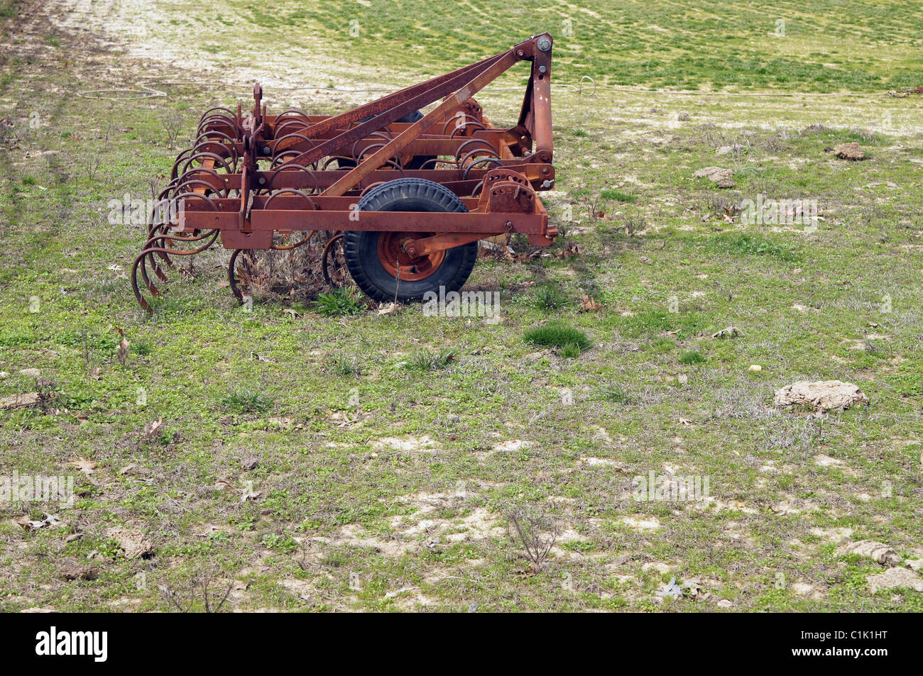 abandoned rusty farm implement in a pasture.  This implement is commonly called a rake Stock Photo