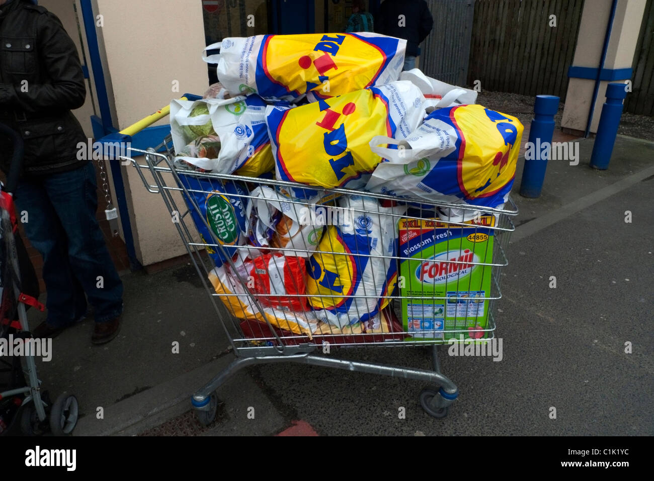 Lidl supermarket shopping trolley overloaded with plastic carrier shopping bags full of groceries outside the store in Great Britain UK   KATHY DEWITT Stock Photo