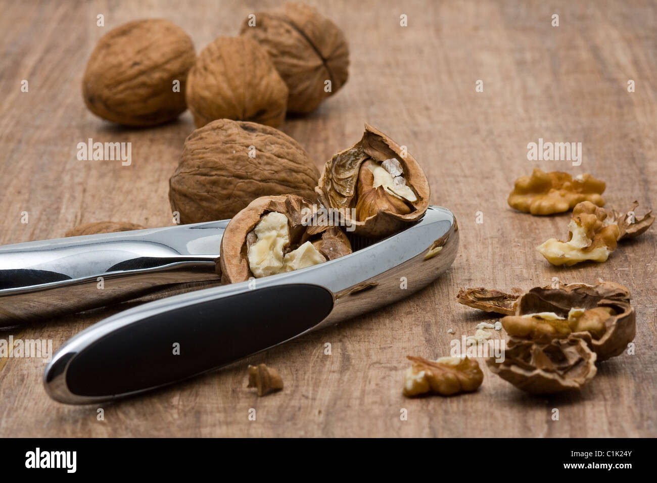 Cracking walnuts with nutcracker on wooden table Stock Photo Alamy
