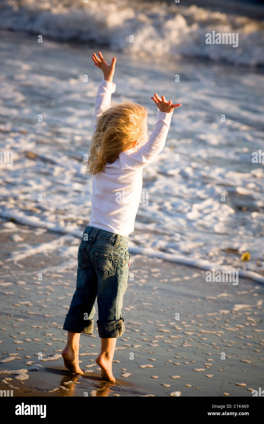 joy, girl, arms up in the air, wind, ocean, sea, beach, summer, fun, playful, jump, dance, youth Stock Photo