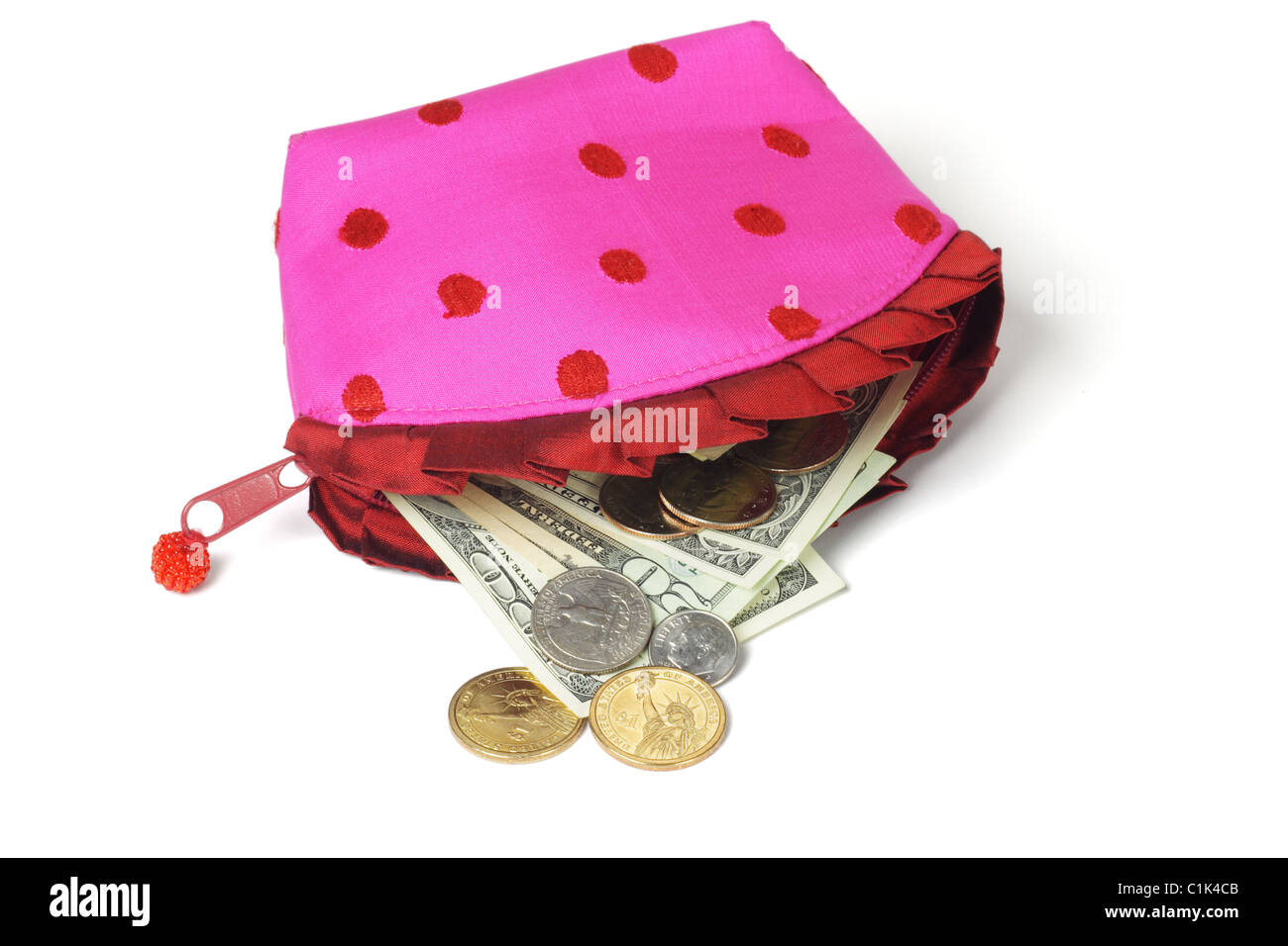 US notes and coins spilling out from pink purse on white background Stock Photo