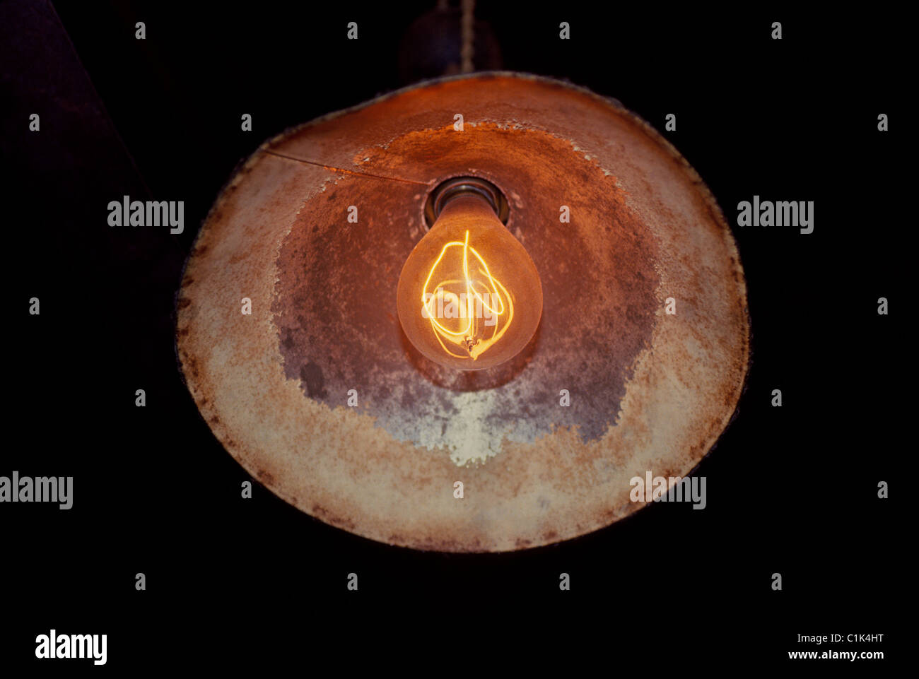 An early incandescent electric light bulb invented by Thomas A. Edison hangs in a vintage light reflector at his laboratory in Fort Myers, Florida. Stock Photo