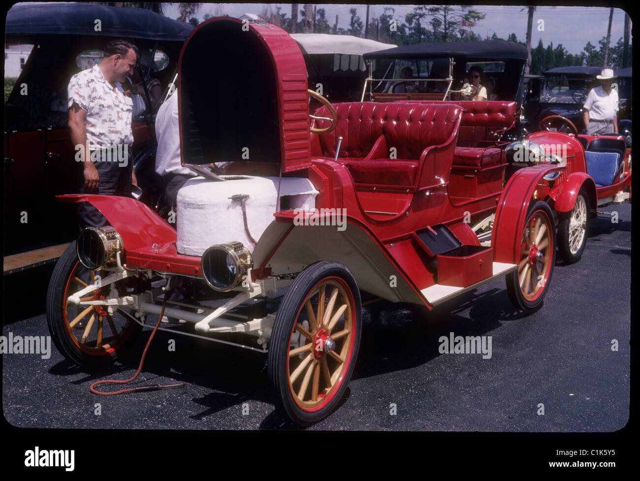 Red antique car at car show during 1950s hood open man looking at Stock Photo