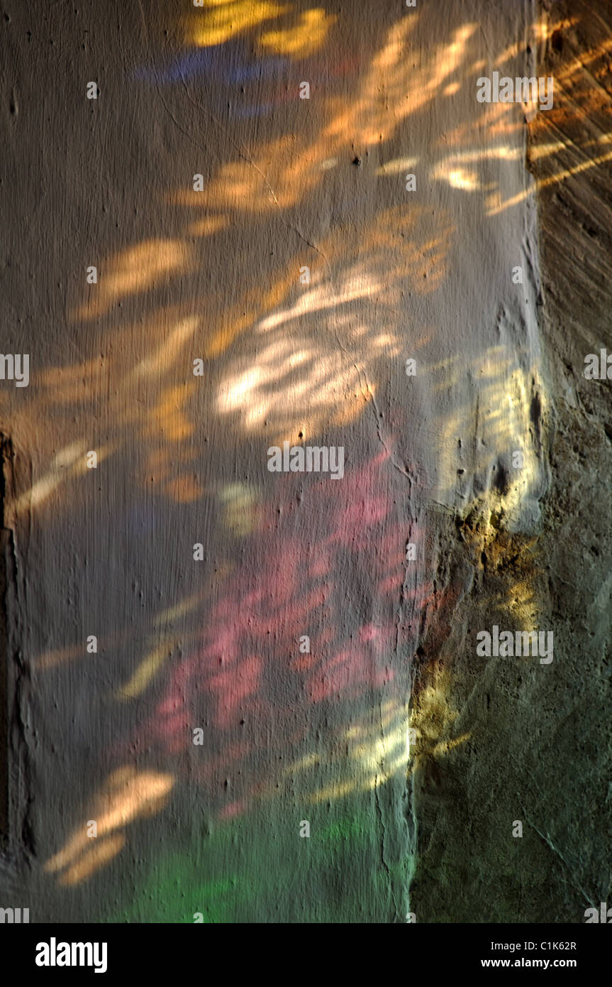 Transmitted light from stained glass on church wall Stock Photo