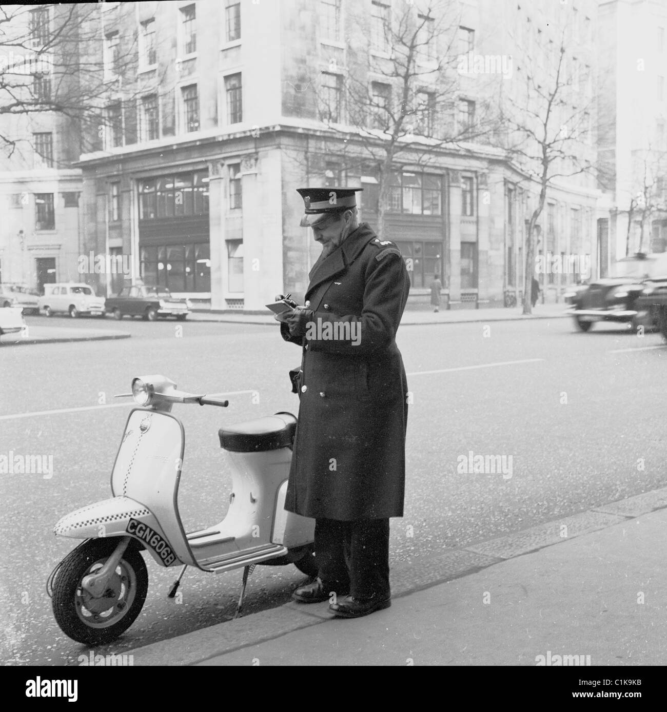 1950s. in this historical picture by J Allan Cash, a traffic warden writes out a parking ticket for a scooter parked incorrectly Stock Photo
