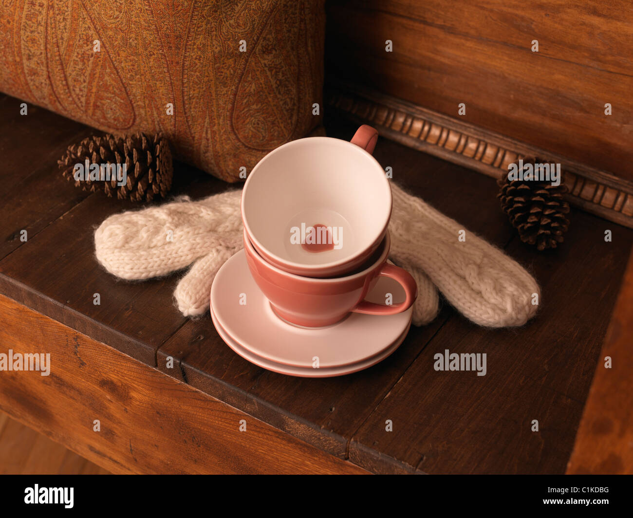 Cups and Saucers, Mittens, and Pine Cones on Bench Stock Photo
