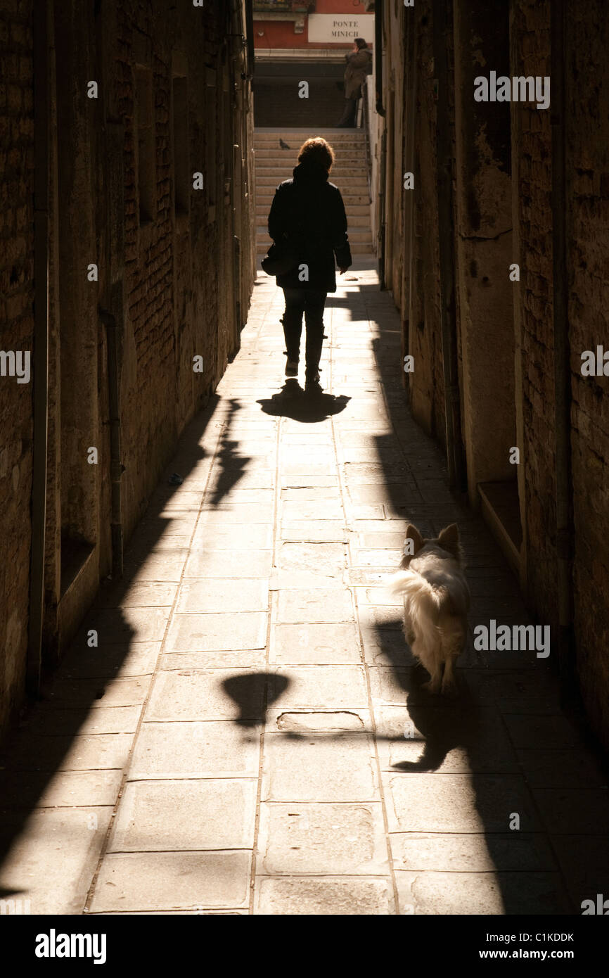 A woman walks her dog in the narrows streets of Venice, Italy Stock Photo