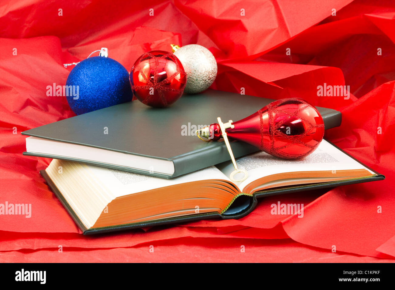 Golden key and open book and closed book on red paper with holiday ornaments reflect the gift that opens knowledge Stock Photo
