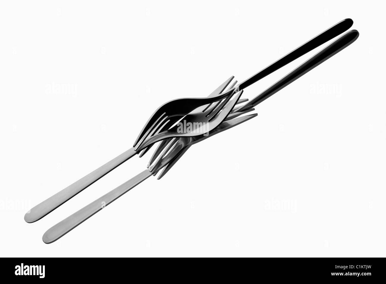 Two forks tangled up on reflecting white background Stock Photo