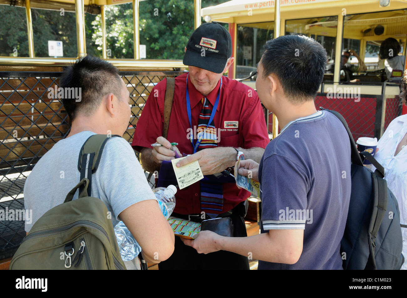 A tram ticket conductor issuing tram tickets to two tourists in Perth, Western Australia Stock Photo